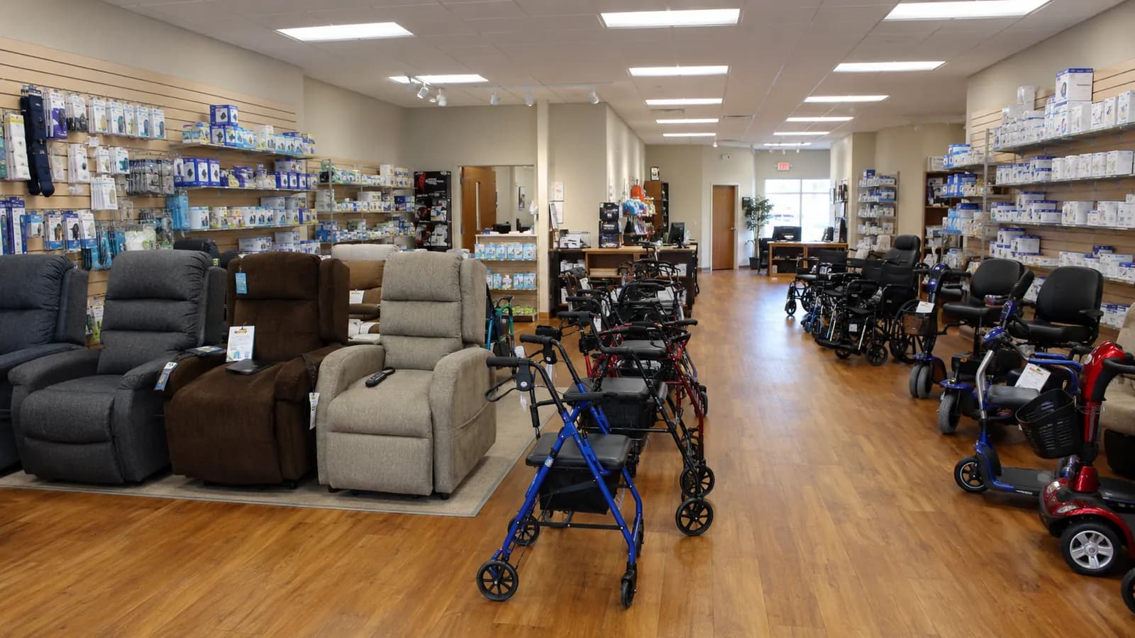 Durable medical equipment showroom with lift recliners, rollators, wheelchairs, mobility scooters, and shelved respiratory and mobility supplies